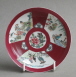 A Chinese ruby ground saucer with famille rose panels, dating from the Yongzheng period