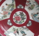 A Chinese ruby ground saucer with famille rose panels, dating from the Yongzheng period