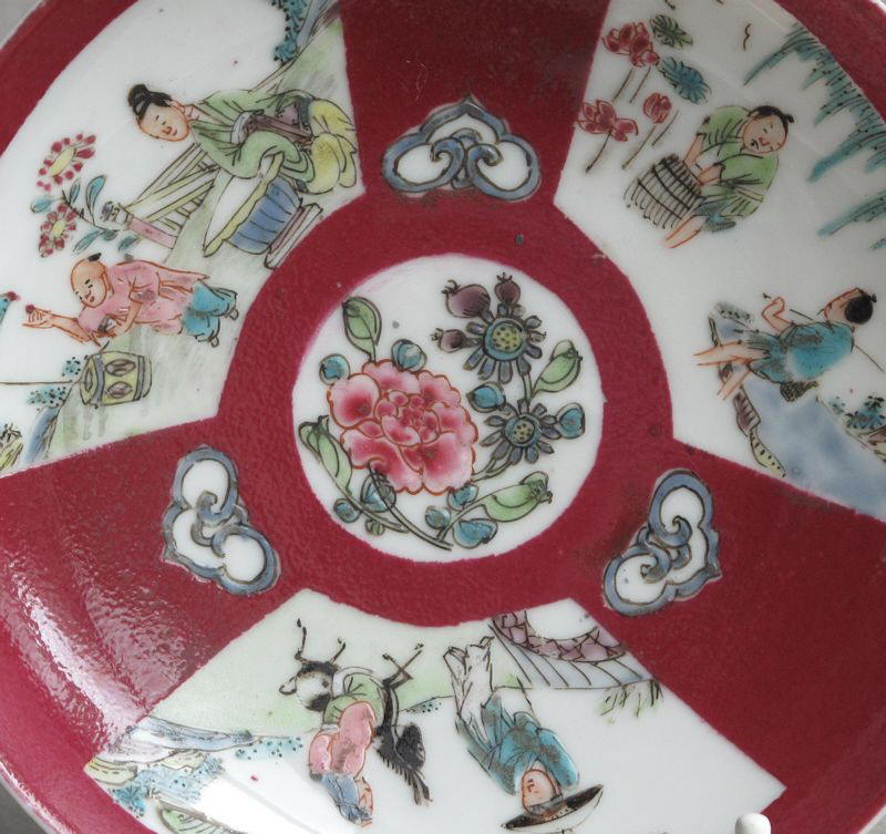 A Chinese ruby ground saucer with famille rose panels, dating from the Yongzheng period